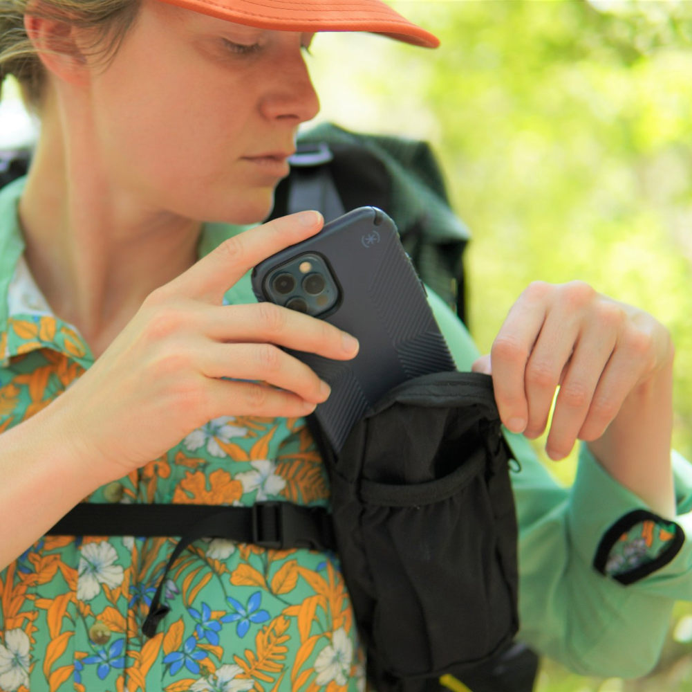 A female hiker puts her phone into the zippered pocket of the ULA Shoulder Strap Pocket
