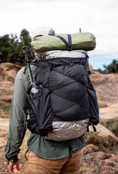 A hiker wears a Nexus frameless pack while backpacking. His tent is strapped to the top using the Y-strap kit.