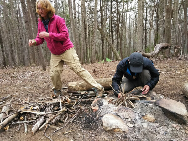 A man and woman stand near a fire ring on the Appalachian Trail