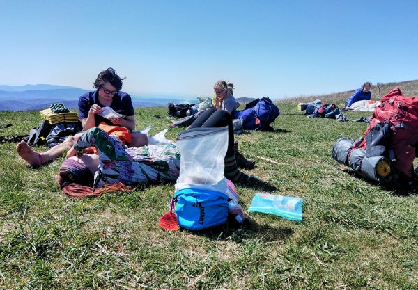 A man eats his lunch on the hillside.