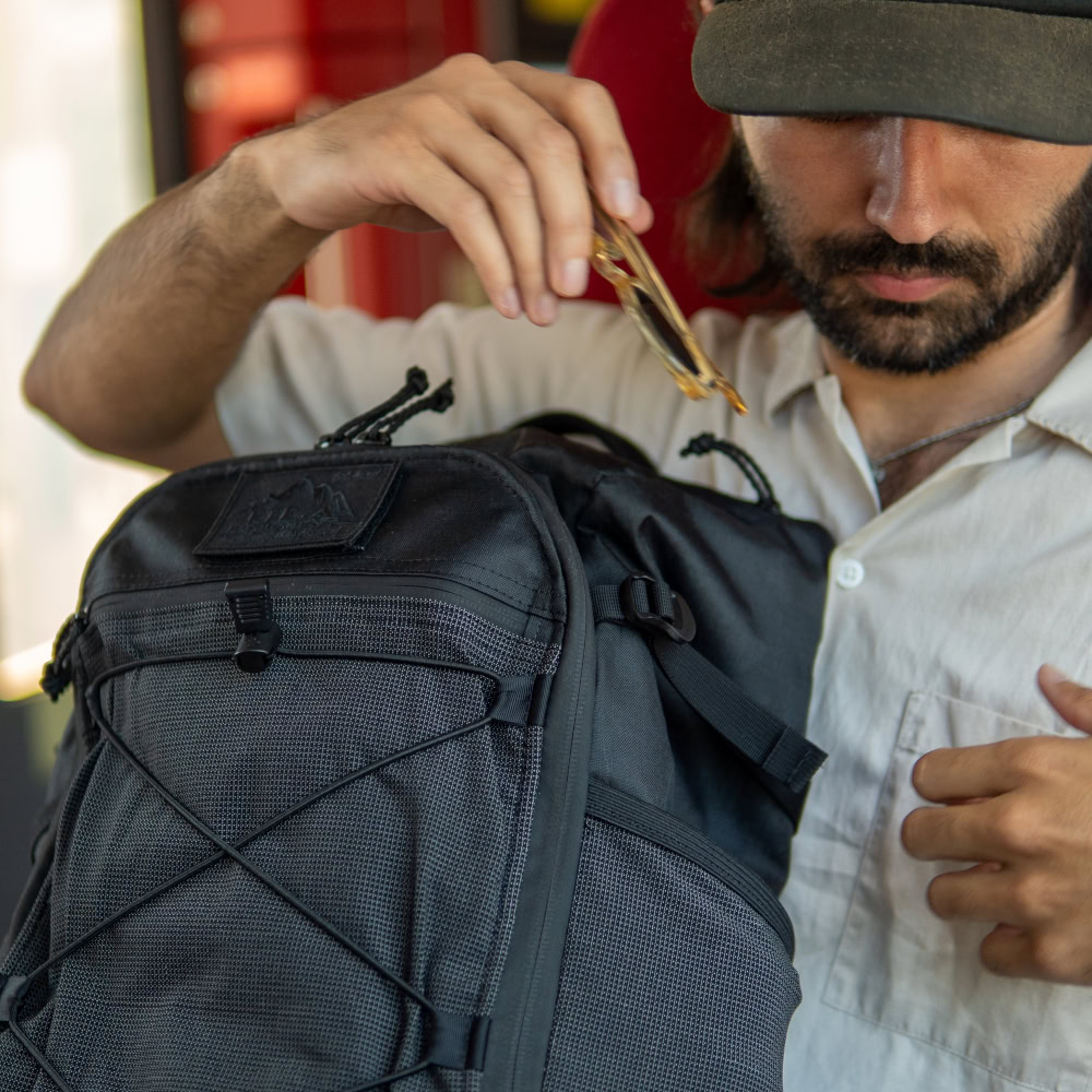 Man on train puts sunglasses into top compartment of ULA EcoPak 36L Dragonfly