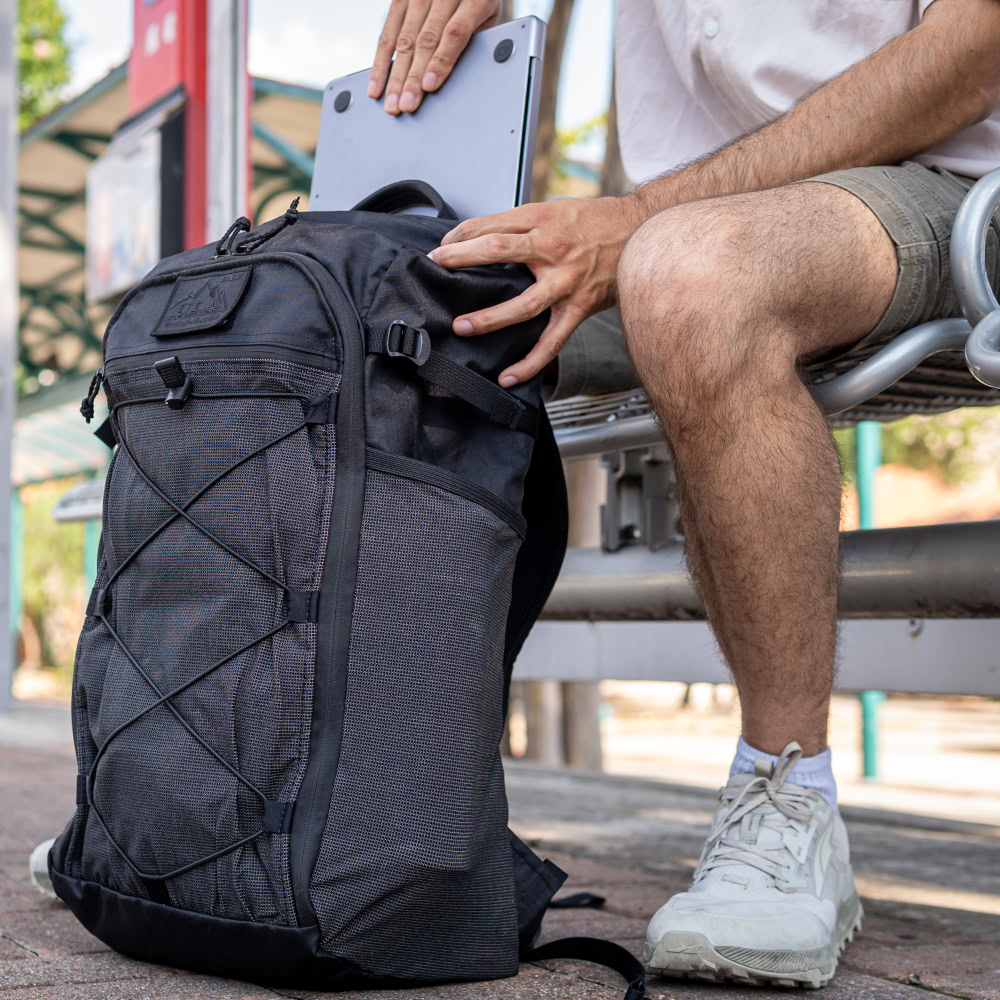 Man sits at train stop with ULA EcoPak 36L Dragonfly