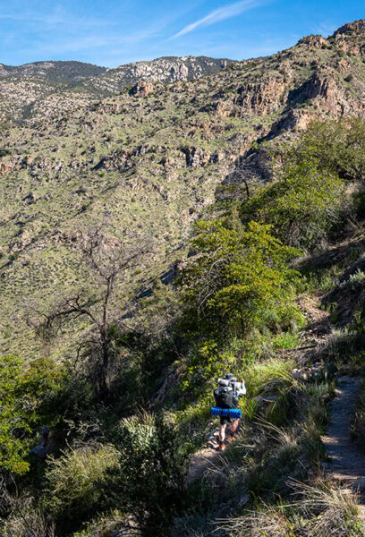 A backpacker climbs up the side of a mountain