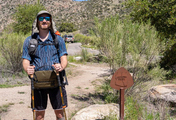 Team member Garrett stands beside an Arizonal Trail marker. He is about to go get his gear dirty.