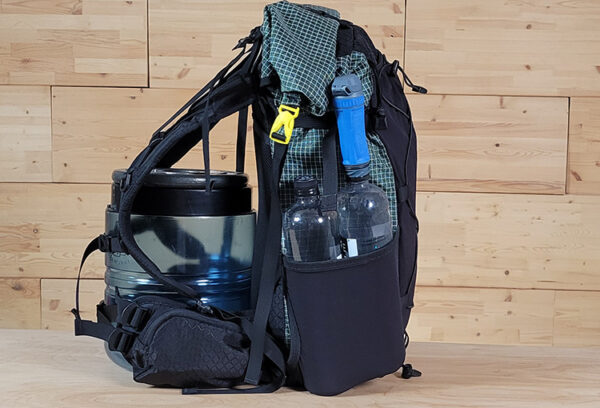 A Kids Spark side view showing how 2 smartwater bottles fit in the side pocket. It is leaned up on a small bear bin to show it could fit.