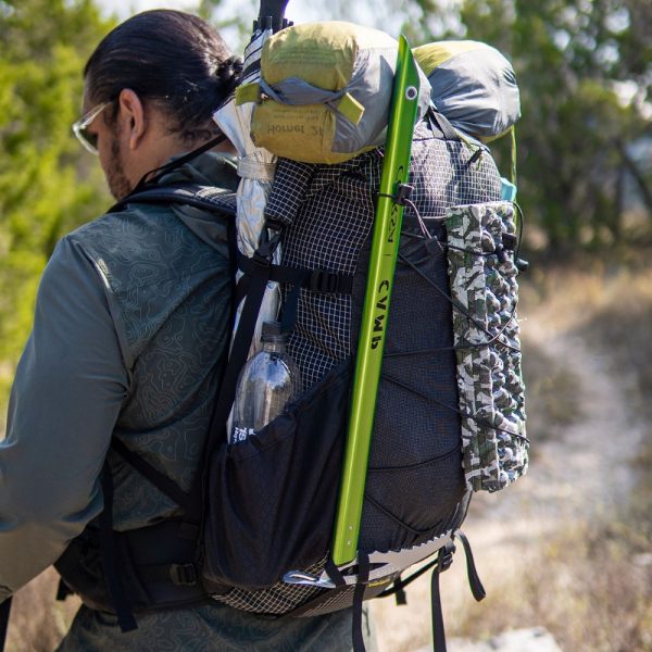 Robic Circuit SV fully loaded on backpacker: they have a tent on the top, a sleeping pad in the front cinch cord, an ice axe in the ice axe loop, and a water bottle and UV umbrella in the side pocket.
