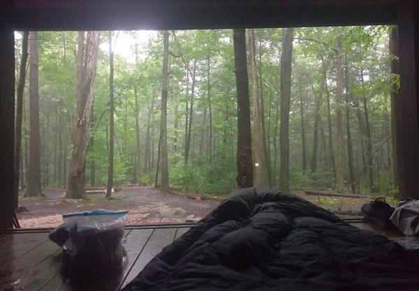 A through hiker in their sleeping bag in an open sided shelter along the Appalachian Trail