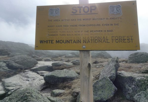 A bright yellow warning sign on the Appalachian trail warning of the worst weather in America and risk of death by exposure in the White Mountain National Forest.