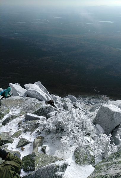 A hiker hikes through a dusting of fresh snow on top of a mountain on the Appalachian Trail