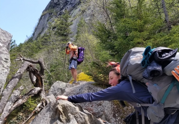 Two hikers boulder up the side of a mountain on the Appalachian Trail.