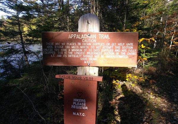 A sign on the Appalachian trail urging hikers to use caution as there is nosupplies or help for the next 100 miles. A min. 10 days supplies is recommended. There is a trail register box below.