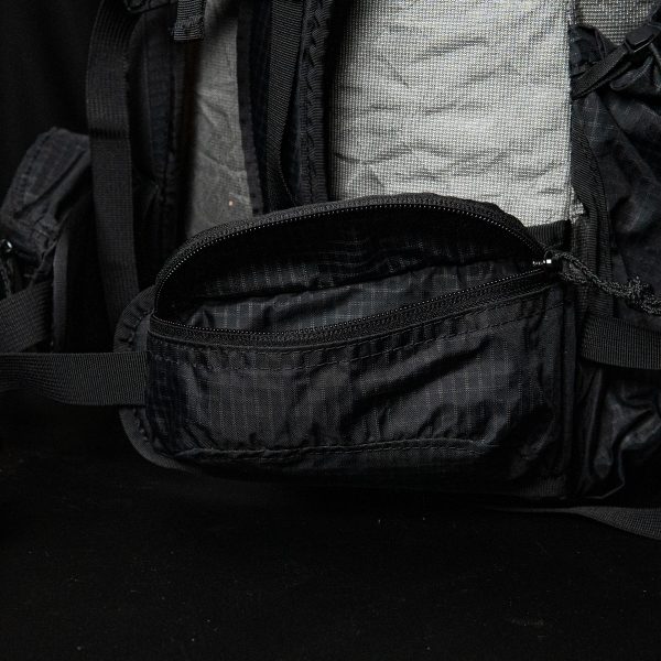 An open ULA Nexus hipbelt pocket. The background is black