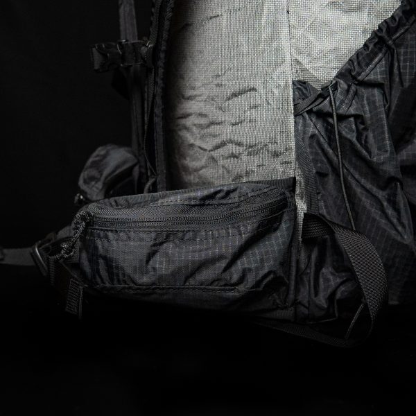 A closed ULA Nexus hipbelt pocket. The background is black.