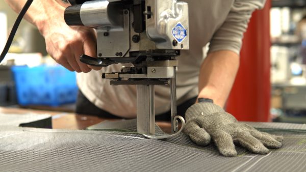 A ULA team member uses a commercial cutting machine to cute through UltrGrid fabric