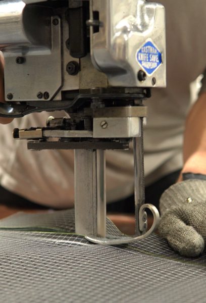 A ULA team member uses a commercial cutting machine to cute through UltrGrid fabric