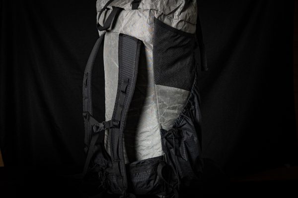A 3/4 back view of the ULA Nexus showing the straps and sternum strap. The background is black.