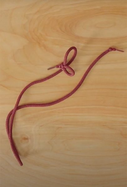 A piece of string sits on a wooden desk top.