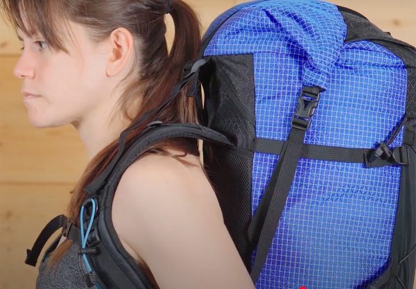 A side view of a backpacker who is wearing a pack that is too tall for her. The shoulder straps lift off of her shoulders, and the load lifters are at the height of her ears.
