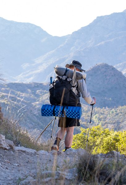 A hiker hikes downhill with a loaded backpack, heading home from a gear and stanima testing trip.