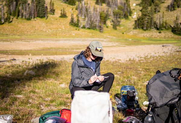 A backpacker digging through her bear canister