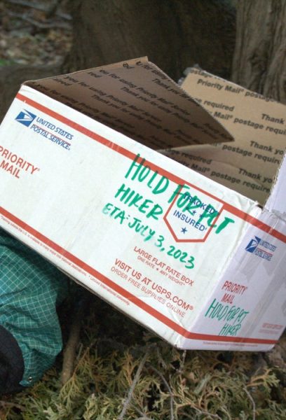A USPS box that has "hold for PCT thru hiker ETA: July 3, 2023" writen on it in large green letters.