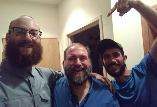 Garrett and two other through hikers smile for the camera. The third hiker is pointing at the second.