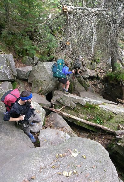 Two thru hikers decend down large boulders on the Apalachian Trail.