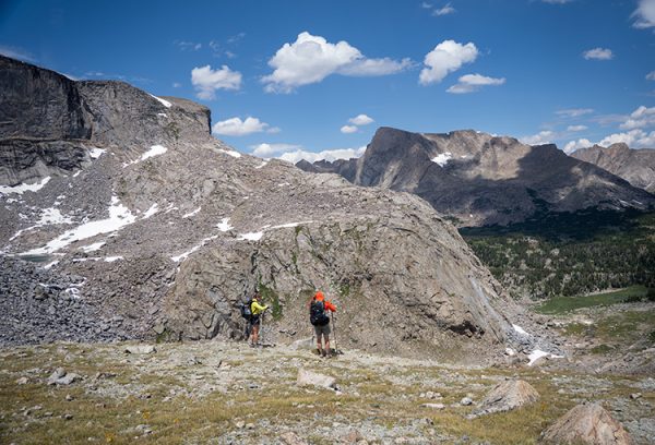 Two backpackers look over the sidfe of a granite mountain in Wyomming.