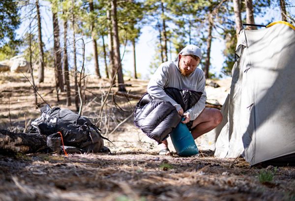 A backpacker stuffs his sleeping bag back into its stuff sack, in preperation of returning to the trail.