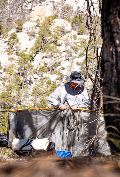 A backpacker sets up his tent in the wilderness.