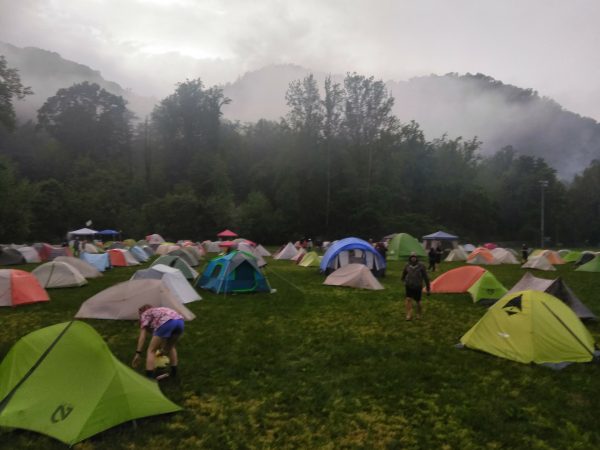 Dozens of tents and campers set up in a large field. It is very foggy and cold looking.