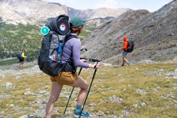A female hiker uses the Y-strap system to carry her bear bin on the top of her backpack while hiking in Wyomming.