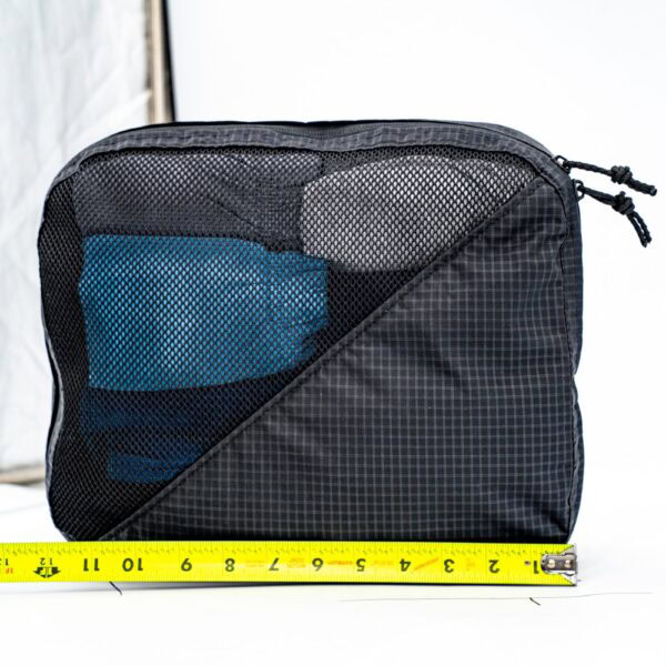 A measuring tape next to the base of a large packing cube. The measuring tape shows the cube is 12" long.