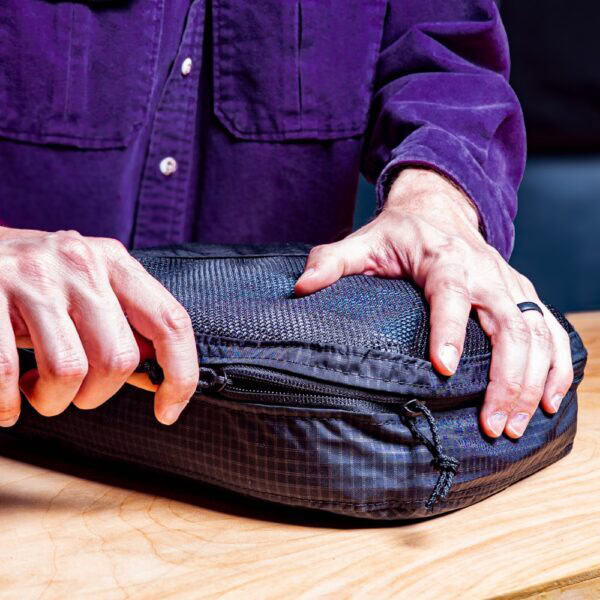 Traveler zips up his ULA packing cube.