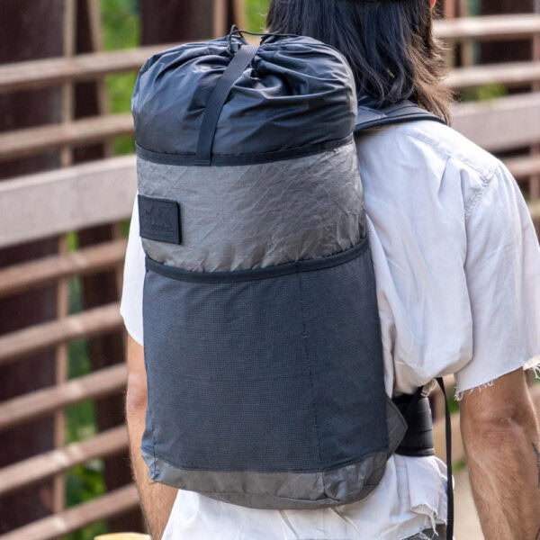 Dayhiker wearing an Ultra Packrat while crossing a bridge in an urban landscape. The color is stuffed, to show expandability.