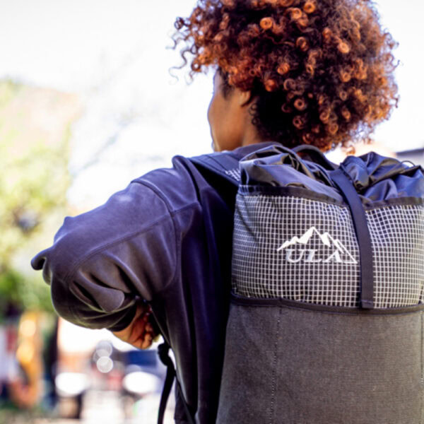 A student wears a black robic ULA Packrat Daypack, image from the back.