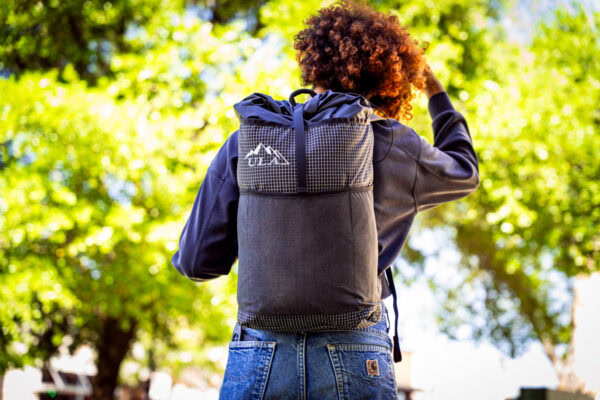 Student wears a black robic ULA Packrat Daypack, image from back.