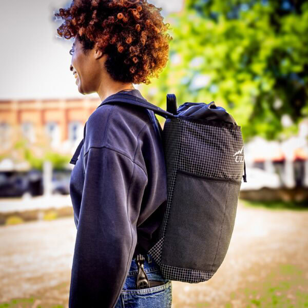 Student wears a black robic ULA Packrat Daypack, image from the side.