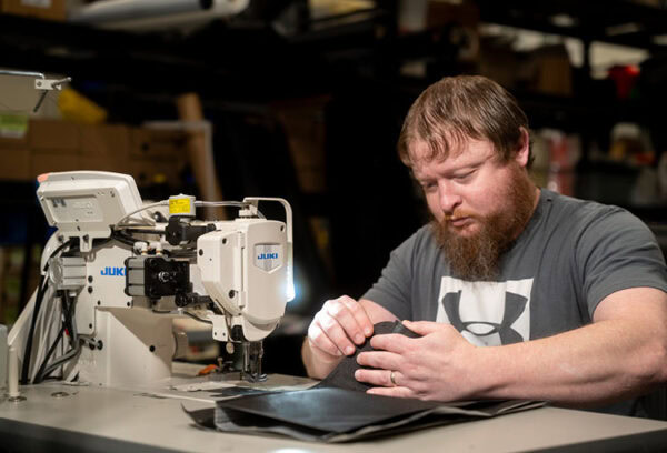A vital team member, Jeremy, sews a pack at a sewing table in Logan, Utah, USA.
