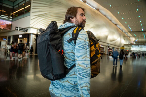 A traveler wears a ULA Node and a custom prototype \dragonfly through an airport