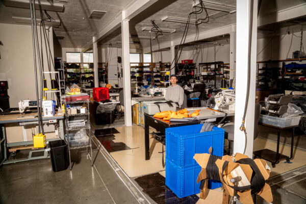 Owen sits at a sewing table on the ULA factory floor. All our gear is made in Logan, Utah, USA.
