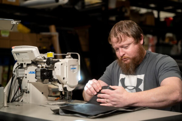A vital team member, Jeremy, sews a pack at a sewing table in Logan, Utah, USA.