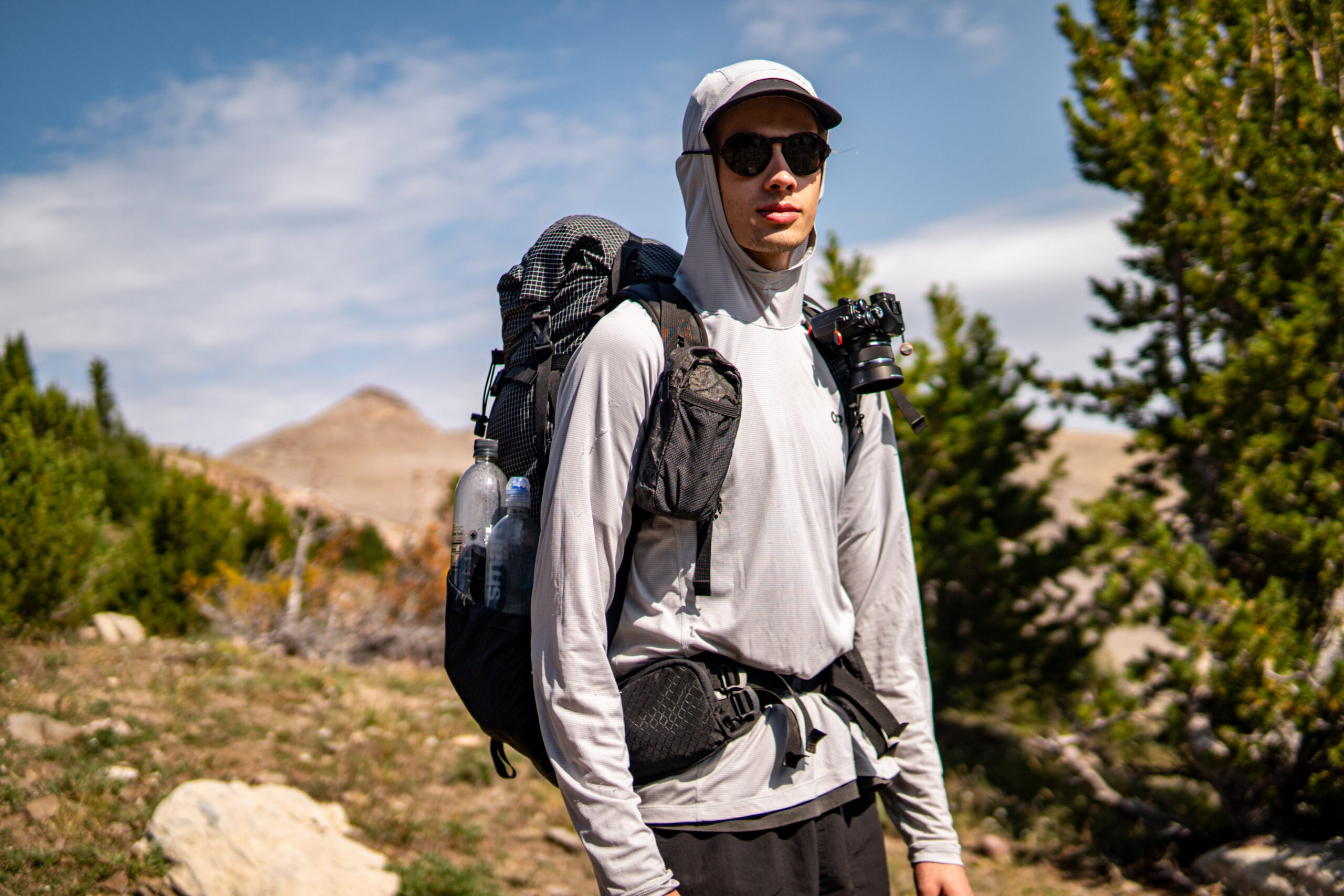 A man wears a backpack and sunglasses in Montana.