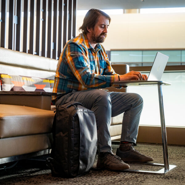 A man at the airport uses his laptop with his ULTRA Cicada next to him