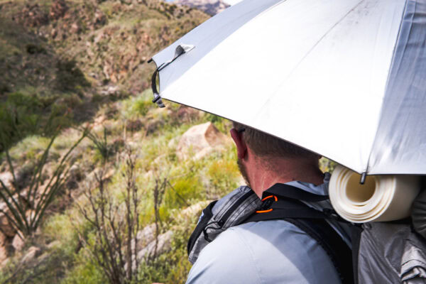A man with a sun umbrella looks out on the Arizona Trail